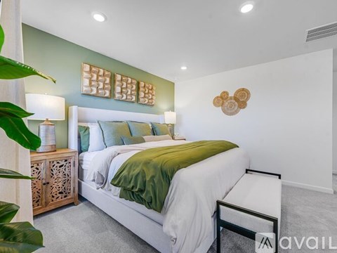 A bedroom with a white bed and green pillows.