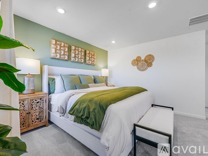 A bedroom with a white bed and green pillows.