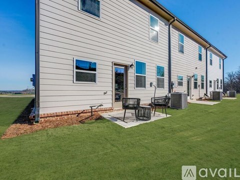A house with a lawn and patio furniture is available for rent.