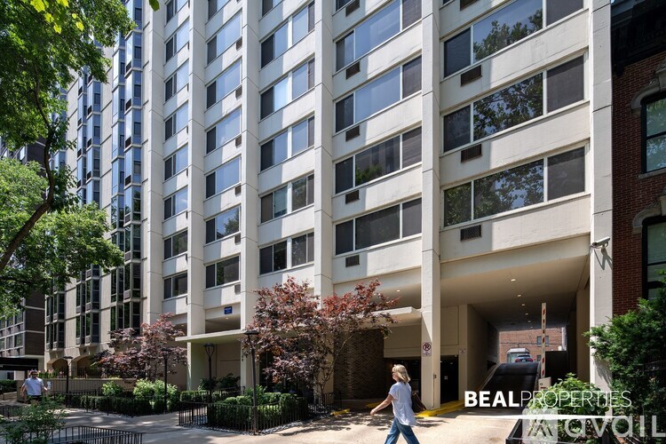 A woman walks in front of a large building with a sign that reads "BEAL PROPERTIES".