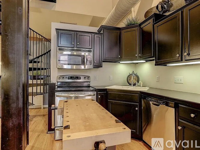 A kitchen with black cabinets and a wooden island.