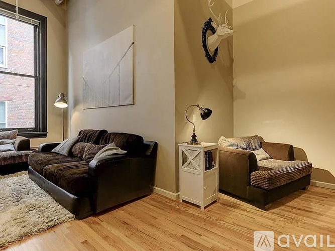 A living room with a large couch and a smaller couch, a lamp, and a painting on the wall.