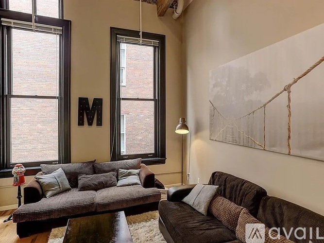 A living room with a brown couch and a large window.