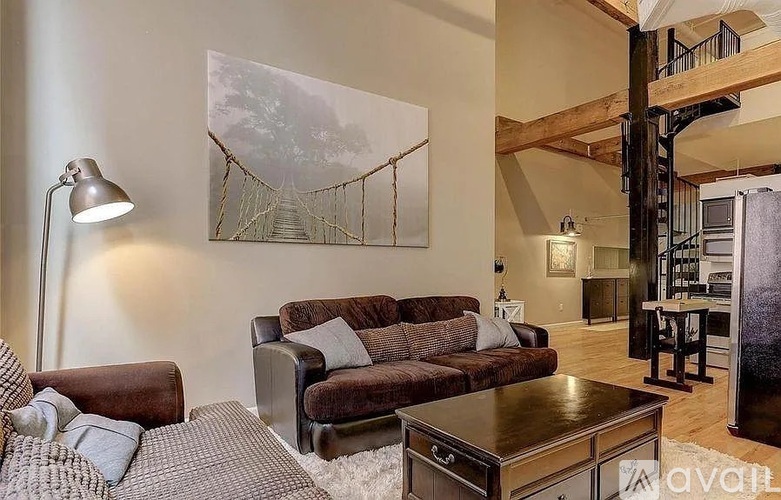 A living room with a brown couch and a painting of a bridge.