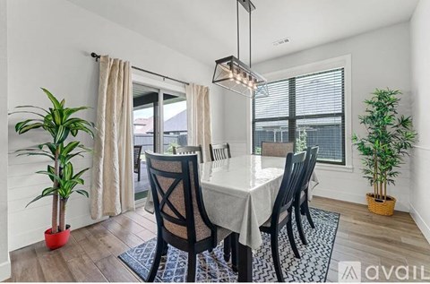A dining room with a table, chairs, and plants.