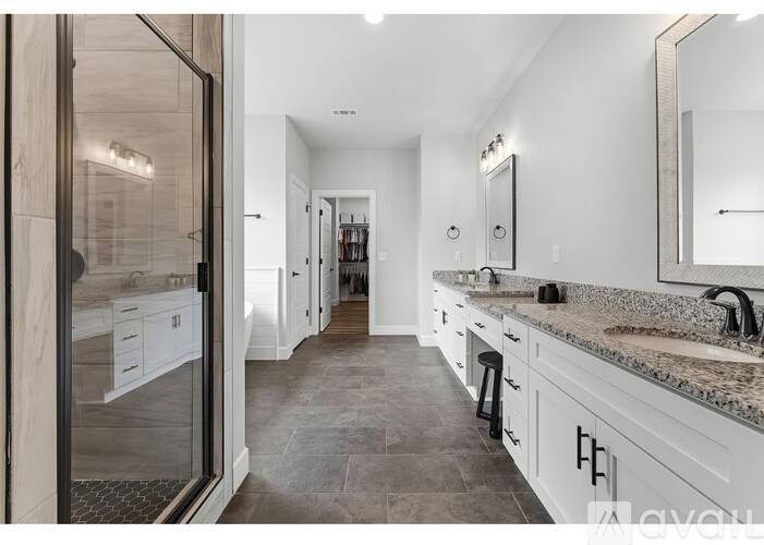A modern bathroom with a walk-in shower and double sinks.