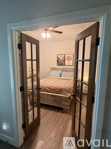 A bedroom with a bed and a ceiling fan is visible through an open door.