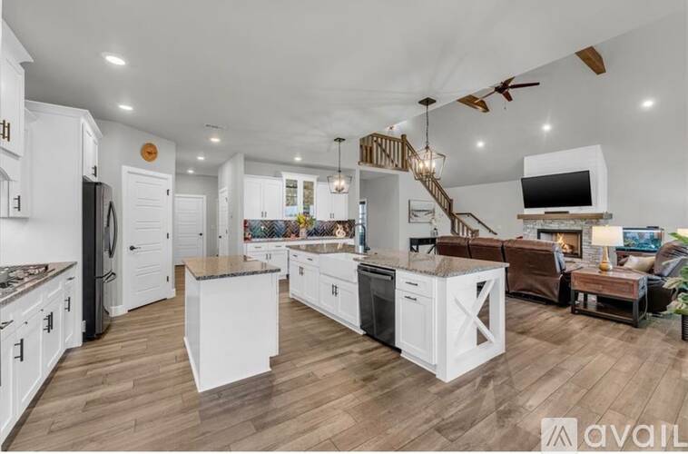 A modern kitchen with white cabinets and a wooden floor.