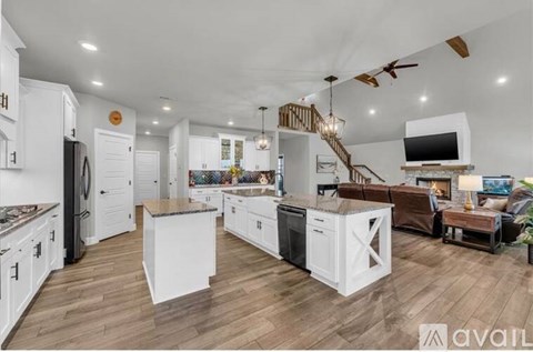 A modern kitchen with white cabinets and a wooden floor.