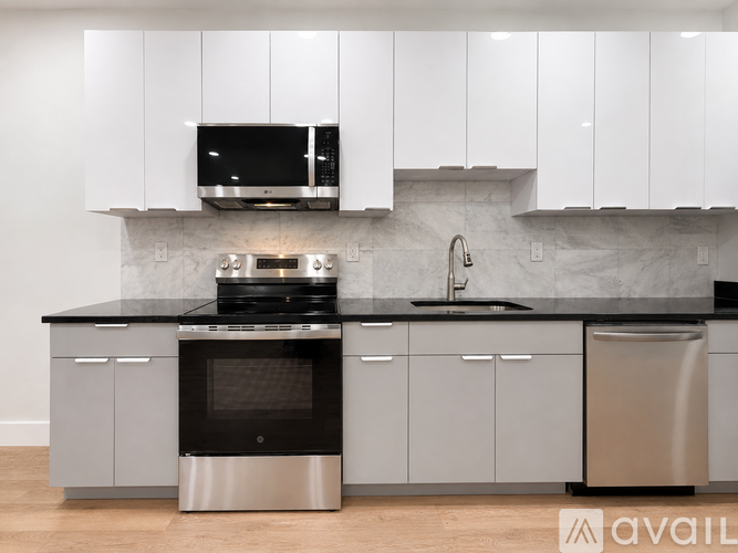 A modern kitchen with a black countertop and stainless steel appliances.