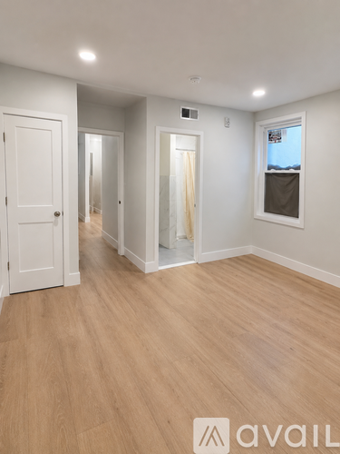 A room with wooden flooring and white walls.