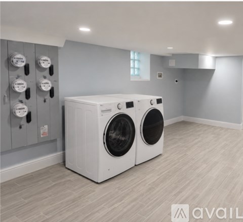 A washing machine in a laundry room with a grey wall.