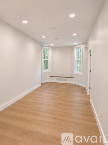 A long, empty room with wooden floors and white walls.