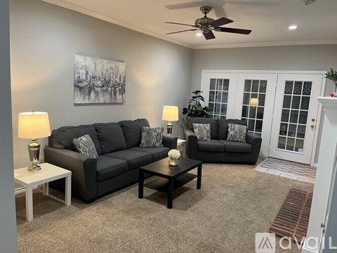 A living room with a grey couch, a black coffee table, and a painting on the wall.