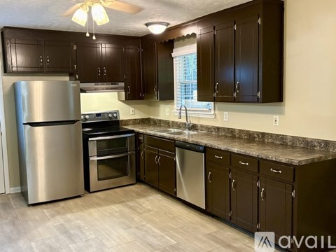 A kitchen with dark brown cabinets and a stainless steel refrigerator.