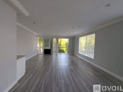 A spacious room with wooden flooring and a large window.