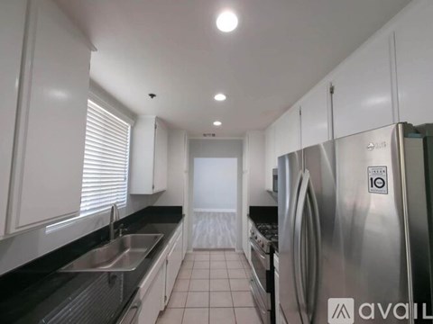 A modern kitchen with white cabinets and stainless steel appliances.
