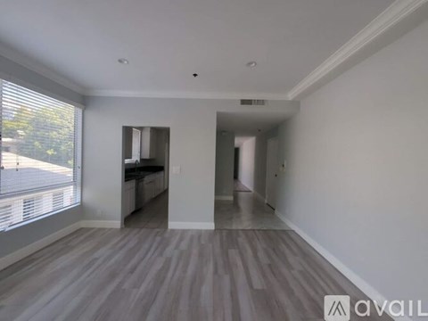 A spacious room with wooden flooring and white walls.