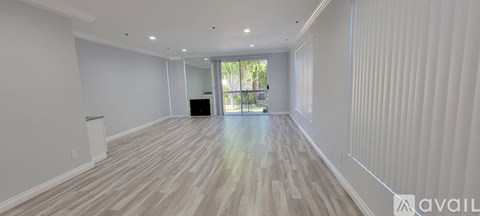 A spacious room with wooden flooring and a large window.
