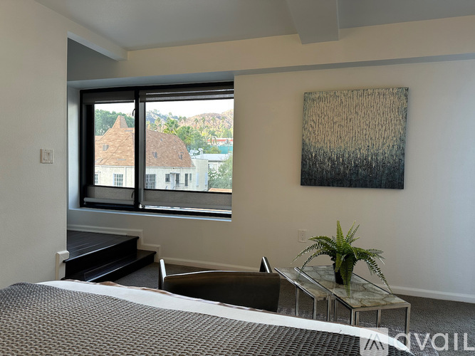 A bedroom with a bed, a table, and a painting on the wall.