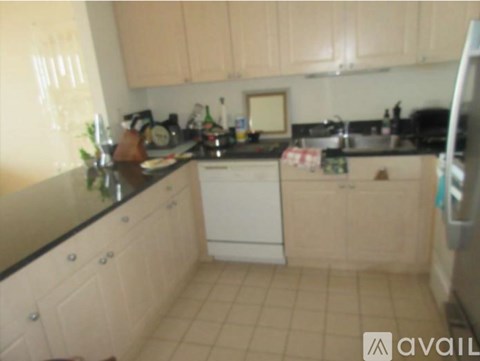 A kitchen with white cabinets and a black counter top.