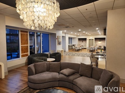 A modern living room with a large grey sofa and a chandelier.