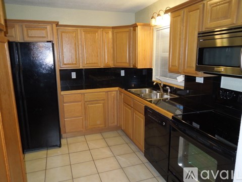 A kitchen with wooden cabinets and black appliances.