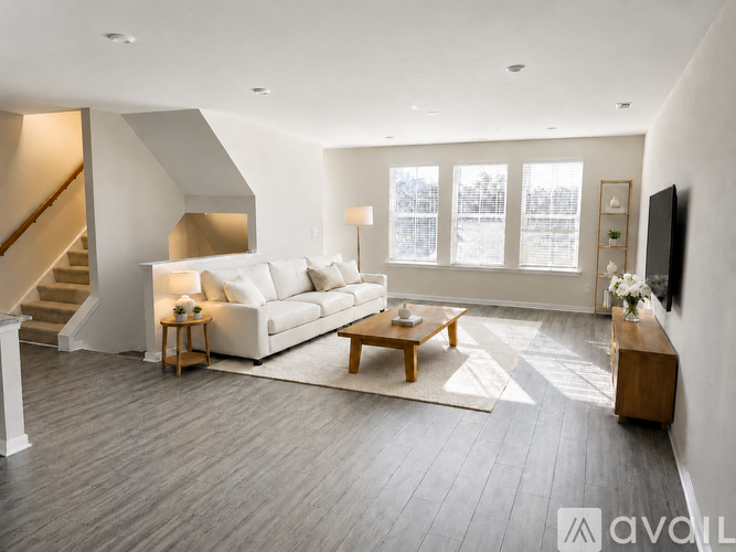 A living room with a white couch, a wooden coffee table, and a staircase.