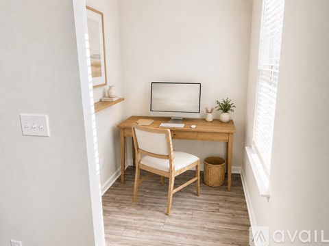 A small desk with a chair and a computer monitor in a corner of a room.
