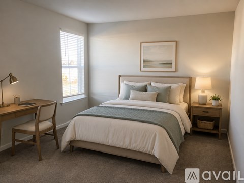 A bedroom with a bed, desk, chair, and window.