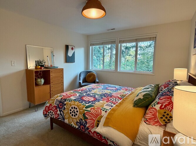 A bedroom with a colorful bedspread and a wooden dresser.