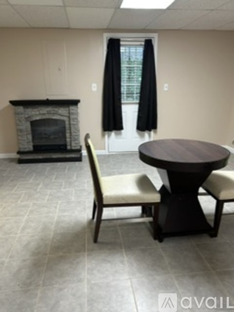 A living room with a fireplace and a table with two chairs.
