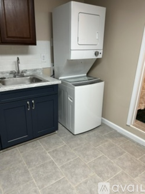 A white dishwasher is in a kitchen with a blue cabinet.