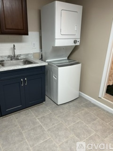A white dishwasher is in a kitchen with a blue cabinet.