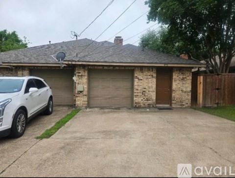 A white car is parked in front of a house with a garage.