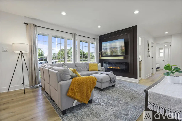 A modern living room with a grey sofa, a yellow throw blanket, and a large painting on the wall.