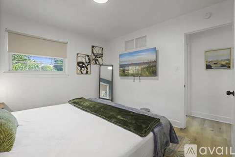 A bedroom with a large bed and a window with blinds.