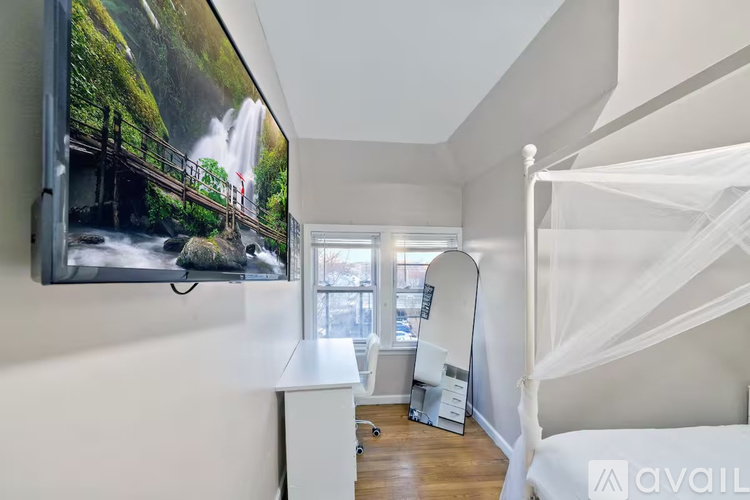 A bedroom with a large TV mounted on the wall and a bed with a white canopy.