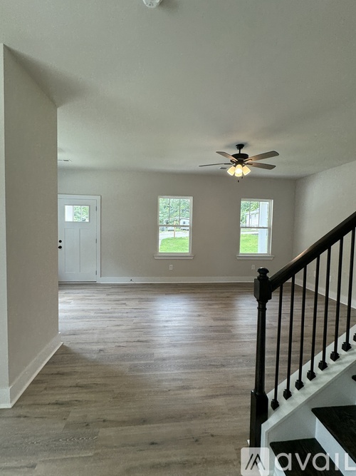 A room with a ceiling fan and a staircase.