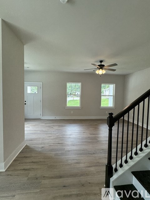 A room with a ceiling fan and a staircase.