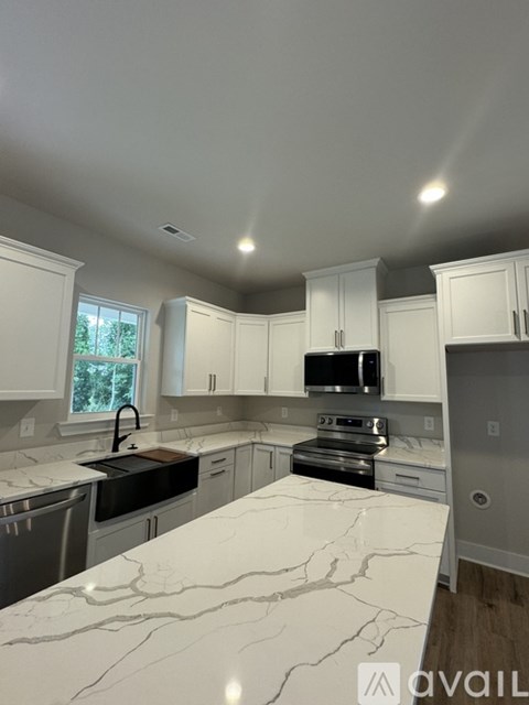 A kitchen with white cabinets and marble countertops.