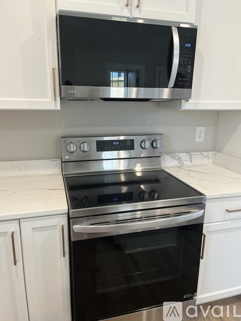 A modern kitchen with a stainless steel oven and microwave above it.