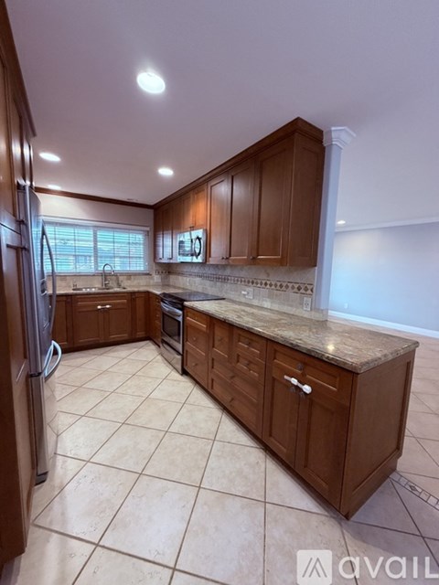 A kitchen with wooden cabinets and a marble countertop.
