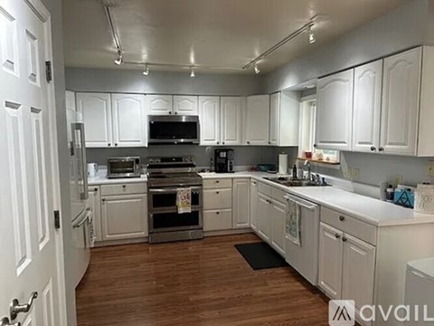 A kitchen with white cabinets and a wooden floor.