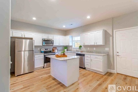A kitchen with white cabinets and a wooden floor.