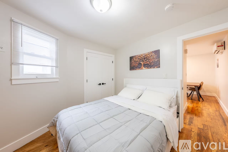 A bedroom with a bed, a window, and a painting on the wall.