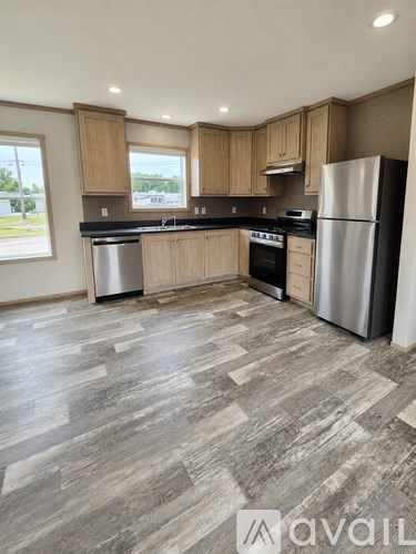 A kitchen with wooden cabinets and a grey floor.