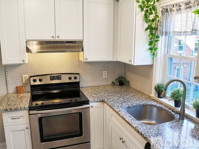 A kitchen with a stove, sink, and white cabinets.