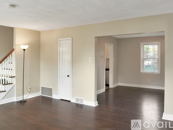 A spacious living room with hardwood floors and a staircase.