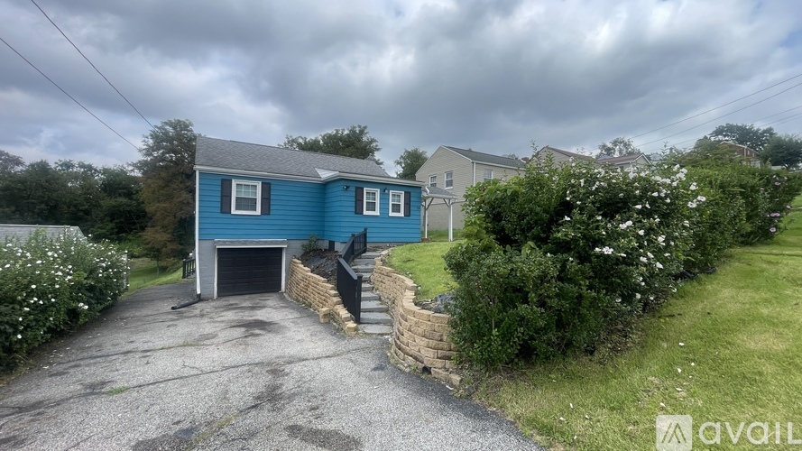 A blue house with a garage and a gravel driveway.